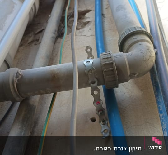 צינורות פלסטיק מחוברים עם מחבר מתכת על קיר